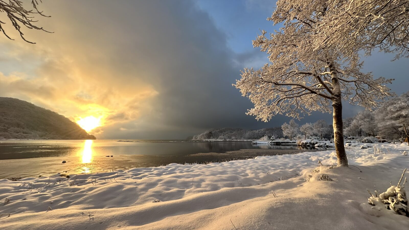 雪景色の湖畔に差し込む朝の光