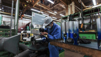 工場で金属部品を確認する作業者